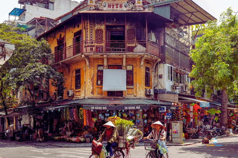 Cyclists passing old colonial houses in Hanoi Old Quarter Vietnam – Auasia Travel